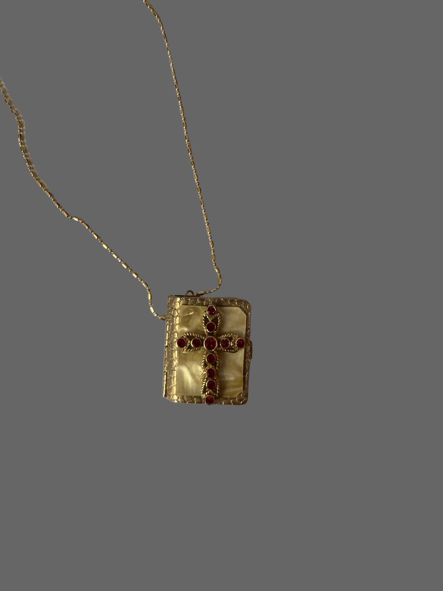 Gold necklace with a rectangular pendant on a white surface