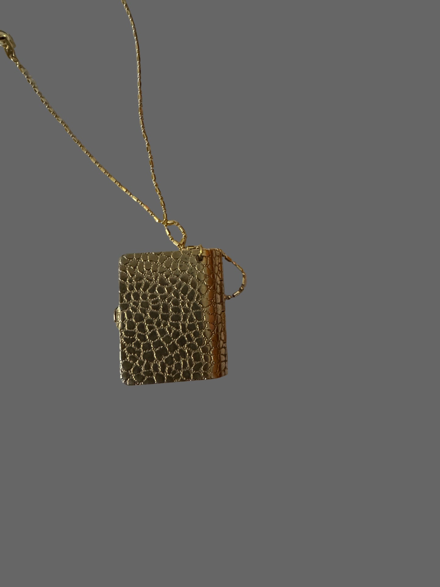 Small textured handbag with a chain on a white surface